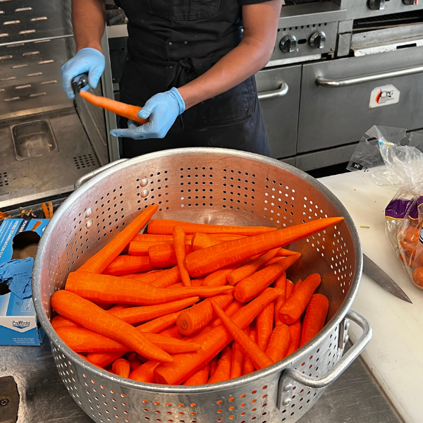 Organic carrots getting peeled in Homespun Kitchen Riverside's open kitchen.